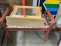 Wood cabinet with mirrored door placed on top of a fabric-upholstered wood bench with curved legs.
