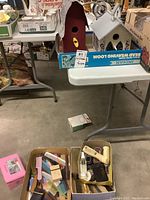 Overview image showing shoe shine brushes, combs, vintage matchboxes, and smokers cases on and below the table.