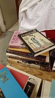 Stack of books mainly featuring costume history and European costume titles with colorful illustrated covers.