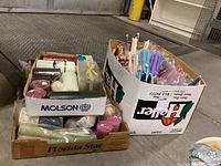 Multiple cardboard boxes containing different candle types with various colors and sizes