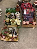 Photo showing assorted ceramic vases, mugs, planters, red plaid blankets, candles, tealight holders, and a tartan stationery box.