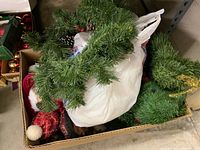 Box with artificial pine tree garlands, some white plastic bags possibly containing other decorations