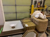 Photo showing large wicker hamper, metal picnic hamper with wood handles, elephant wall sconce on top, and a square light shade to the side.