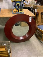 Front angled view of round mirror with reddish-brown wooden frame, showing size and condition.