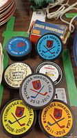 Top view of all seven Rychnovská Hockey League souvenir pucks, Toronto Maple Leafs 1961-1962 Stanley Cup Champions puck, and boxed skate sharpener model 60.