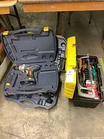 Overall lot showing open Mastercraft power drill case, plastic toolbox with tools, and yellow case for spin saw kit