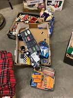 Photo of various toy cars, Lego pieces in cardboard boxes, and a pack of crayons.