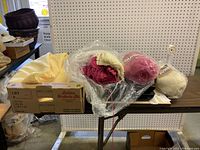 Image showing yarn skeins, knit scarves and a box with Dahle paper cutter model 115 packaging, along with folded tablecloths and napkins on a table.