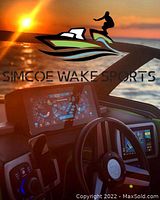 Boat dashboard with Simcoe Wake Sports logo displayed on digital screen at sunset