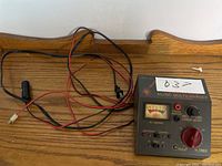 AC/DC multi charger showing device with attached cables and connectors laid on wooden surface.