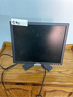 Front view of Dell monitor on wooden desk, showing screen and stand