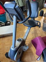 Side view of the exercise bike showing the padded seat, handlebars, and base frame.