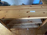 Front view of wooden kitchen island showing open shelves under top surface and natural wood construction.