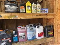 Shelf with assorted automotive fluids including diesel oil, transmission fluid, power steering fluid, motor oils, and battery isolator box