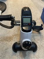 Photo of the under desk bike with digital monitor, pedals, and adjustable knob.