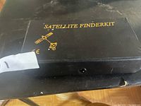 Closed black carrying case with 'SATELLITE FINDERKIT' text and satellite graphics.