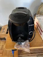 Front view of Bosch Tassimo coffee machine showing pod insertion area, front power button, and branding