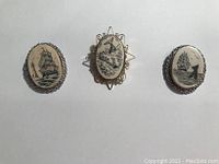 Three nautical themed pins with oval black and white illustrations and metal frames on a white background