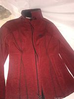 Red ladies medium Harley Davidson jacket laid out flat showing front side with stand-up collar and zipper.