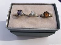 Top view of three rings in cushioned jewelry box highlighting gemstone colors and band styles
