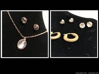 Side view of necklace with oval pendant and stud earrings with clear rounded stones on black display.