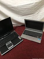 Overview photo of two laptops, one black with visible Toshiba Tecra branding, and one silver laptop of unknown model.