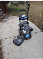 Full view of Powerstroke pressure washer with coiled high-pressure hose and driveway cleaning attachment on ground