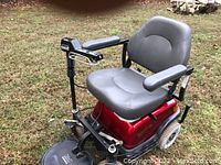 Side view of scooter showing red base, grey vinyl seat, tiller and front wheels