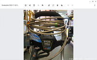 Close-up of Ryobi 3100 PSI control panel with coiled metal hose.