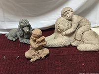 All three statues shown together on a burgundy carpeted surface against a white cloth backdrop to illustrate size and details of yard decor set