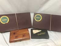 Four vintage game sets: two Scrabble sets in brown cases, one black boxed dominoes set, one wooden Cribbage board.