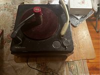 Top and angled view of one RCA antique record player, showing red felt turntable pad, tone arm, and control knobs.