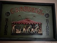 Front view of antique carved out carousel sign with detailed carousel and horse figures, text 'CAROUSEL 5c Rides'