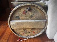 Close-up view of the round wooden churn base with visible floral painted decoration and an electric wire attached indicating conversion to speaker.