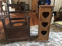 Image showing both antique wooden potty chair and toilet paper holder placed on a rug in a room with wooden floor.