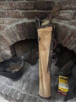 Photo of antique golf clubs inside original golf bag standing upright near a brick fireplace.