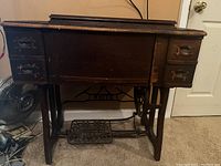 Frontal view of the antique White sewing machine cabinet with treadle and drawer details