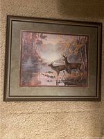 Photo of framed and matted print showing two deer (buck and doe) at river camp site with autumn trees.