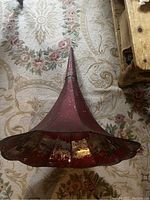 Top-down view of the antique phonograph horn placed on floral patterned carpet showing flared bell shape and scalloped edges.