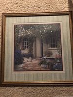 Full view of framed print showing the stone cottage with flowers in pots at entryway.