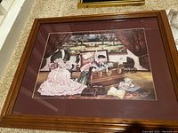 Photo of framed and matted print showing detailed vintage interior scene with clothing and objects.