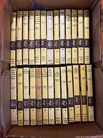 Books arranged standing upright in a box showing spines with titles and series logo.