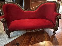 View of Victorian style toddler coach with red velvet upholstery and carved wooden frame