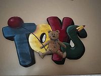 Front view of the wood carved 'TOYS' sign with teddy bear and duck decorations
