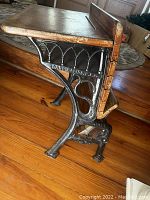 Side close-up showing wooden desk top and seat with cast iron leg bearing the brand name 'Grand Rapids MFG CO'