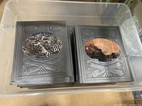 Plastic bin holding the Civil War book set, showing two stacks of books with silver embossed covers and colored historic images on the front.