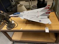 Side and top angle view of the large Tomcat F-14A model airplane placed on a wooden table, showing its size relative to a nearby table fan.