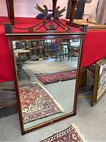 Full view of antique wood mirror reflecting surrounding area and floor rugs, showing its rectangular shape and size.