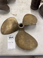 Top view of the three-blade brass or bronze propeller showing smooth blades and central mounting hole with visible wear.