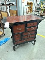 Front angled view showing the reddish-brown wood drawer fronts with black framing and brass hardware.